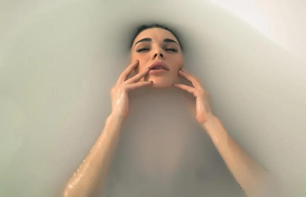 Fine art color milk bath boudoir portrait focusing on facial expression and hands.